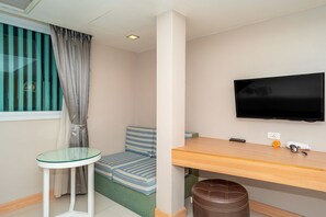 A room with a bed, a TV, a small table, a chair, and a window with curtains. - Ratana Platinum Resort Kamala (Kamala)