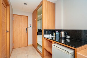 Una cocina compacta con armarios de madera, una encimera negra y un refrigerador pequeño.