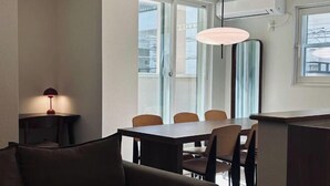 A modern dining area with a rectangular table, four chairs, a pendant light, and a sofa. - URBAN HOUSE KOENJI (Tokyo)