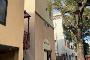 Un edificio con balcón, un árbol y cielo despejado.