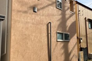 A building facade with a window, a door, and a small light fixture. - URBAN HOUSE KOENJI (Tokyo)