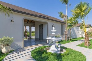 A house with a covered patio, a fountain, and a garden with palm trees. - Chunnchay Bed&Restaurant (Mae Wang)