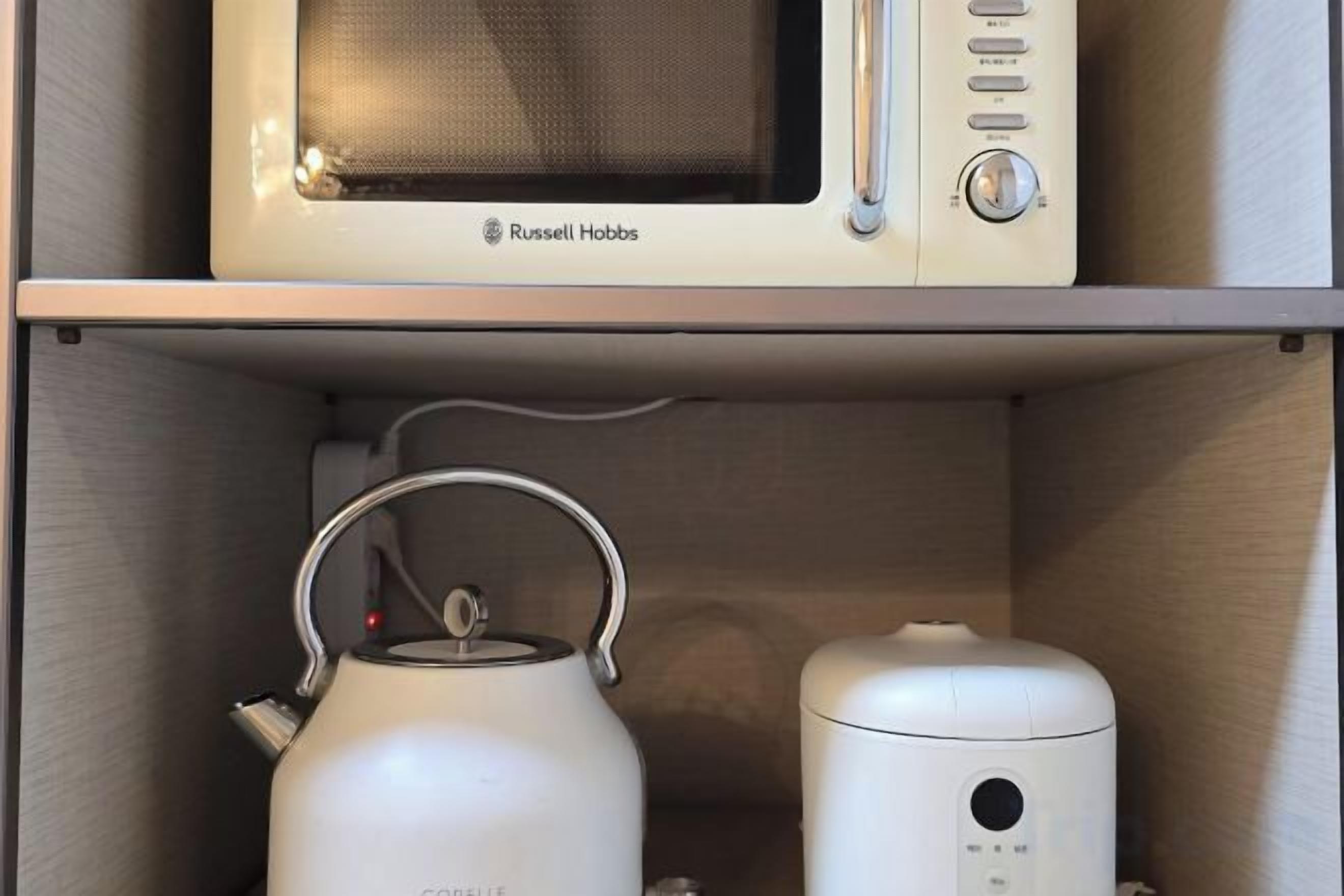 Cozinha compacta equipada com micro-ondas e chaleira.
