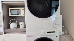 Een kleine keuken met een magnetron, waterkoker en een wasmachine.