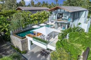 A modern house with a glass balcony, a swimming pool, and lush greenery. - Sava Villa 6 Villa Roxo (Takua Thung)