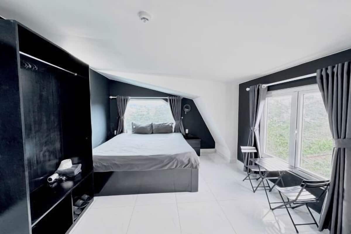 A modern bedroom with a bed, a desk, and a window with curtains.