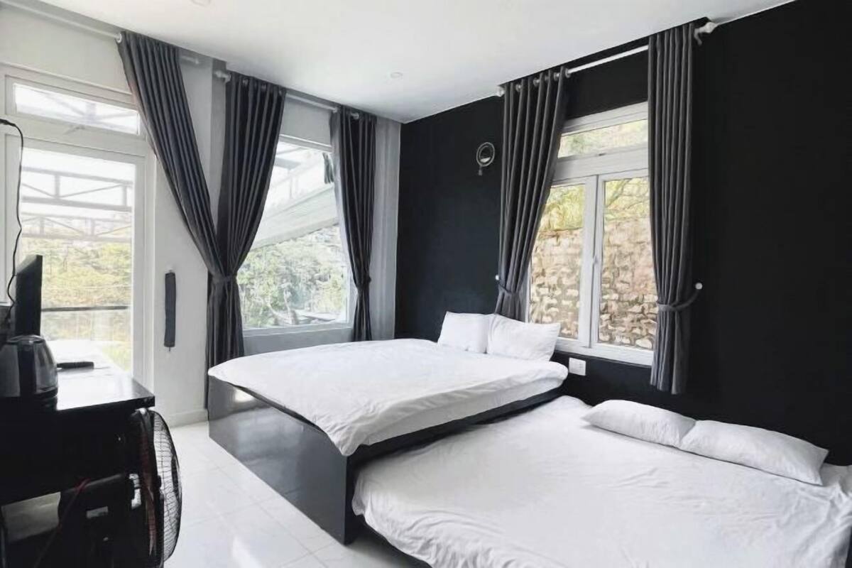 A bedroom with a bed, a desk, and a fan.