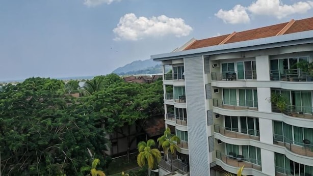 A multi-story building with balconies, large windows, and a view of a mountainous landscape. - Langkawi Perdana Families Suite @ Langkawi Airport (Langkawi)