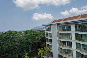 A multi-story building with balconies, large windows, and a view of a mountainous landscape. - Langkawi Perdana Families Suite @ Langkawi Airport (Langkawi)