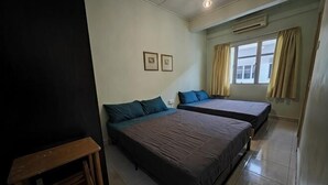 A room with two beds, a wooden table, and a window with curtains. - Langkawi Perdana Families Suite @ Langkawi Airport (Langkawi)