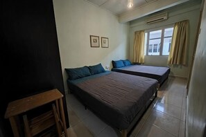A room with two beds, a wooden table, and a window with curtains. - Langkawi Perdana Families Suite @ Langkawi Airport (Langkawi)