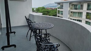A balcony with a round table and chairs, a blackboard, and a view of buildings and greenery. - Langkawi Perdana Families Suite @ Langkawi Airport (Langkawi)