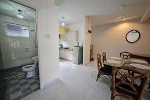 Une cuisine de taille réduite comprenant un réfrigérateur, une table à manger avec des chaises et un miroir au mur.