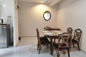 Un coin repas avec une table et des chaises, un réfrigérateur et un miroir fixé au mur.