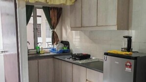 A kitchen with wooden cabinets, a refrigerator, and a window with curtains. - Langkawi Perdana Families Suite @ Langkawi Airport (Langkawi)