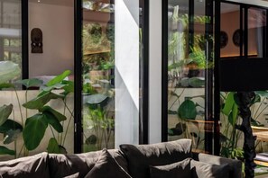 A modern interior with a sofa, large windows, and indoor plants. - Villa Swing by BaliSuperHost (Bali)
