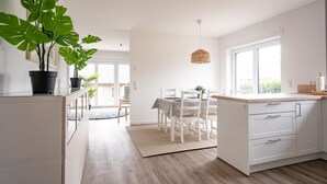 A modern kitchen with white cabinetry, a wooden countertop, and a large window.