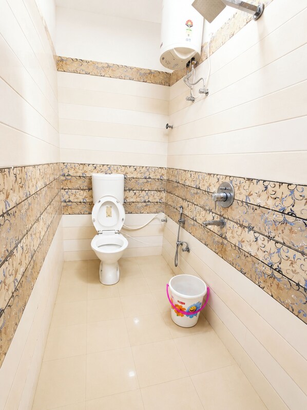 A bathroom with a toilet, a shower, and a bucket. - Hotel Swastik Guest House Varanasi (Varanasi)