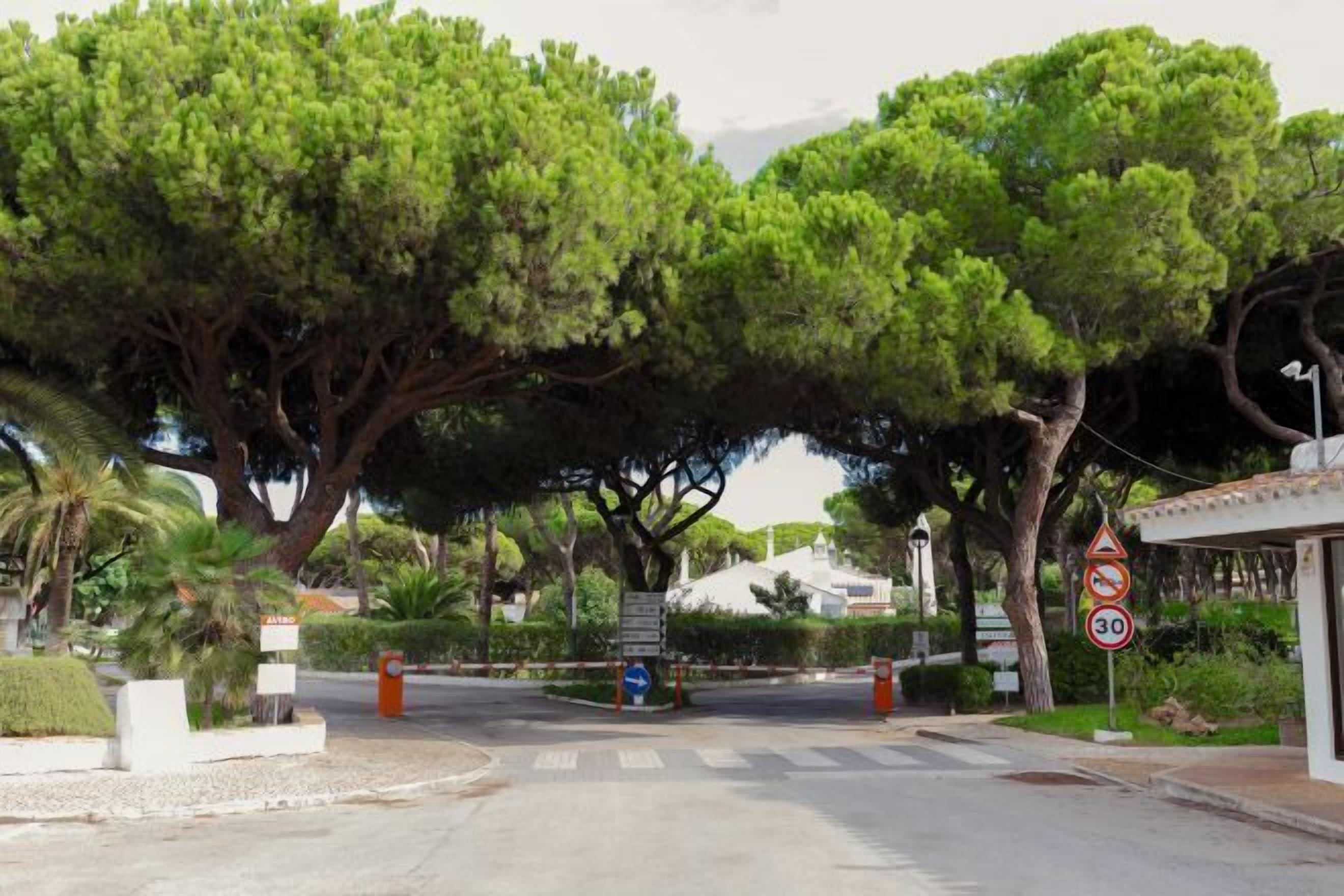 A gated entrance with a speed limit sign of 30, surrounded by lush greenery and trees.