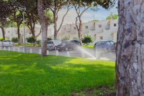 A residential area with parked cars and a sprinkler system. - BnB Homes Falésia Beach Cozy Apartment with Terrace & 2 Swimming Pools (Olhos de Agua)