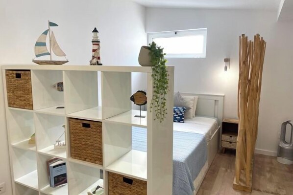 A bedroom with a bed, a white shelving unit with decorative items, a window, and a wooden structure. - BnB Homes Falésia Beach Cozy Apartment with Terrace & 2 Swimming Pools (Olhos de Agua)
