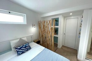 A bedroom with a bed, a window, a wardrobe, and a decorative wooden screen. - BnB Homes Falésia Beach Cozy Apartment with Terrace & 2 Swimming Pools (Olhos de Agua)
