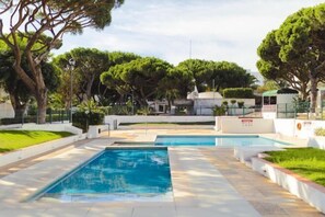 A pool area with two rectangular pools, surrounded by well-maintained greenery and a white fence. - BnB Homes Falésia Beach Cozy Apartment with Terrace & 2 Swimming Pools (Olhos de Agua)