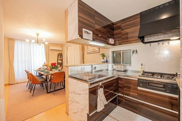 A modern kitchen with a central island, built-in appliances, and a dining area with chairs and a table. - 1-min sta/Asakusa/Ueno/Ginza/Skytree/Narita/Haneda (Tokyo)