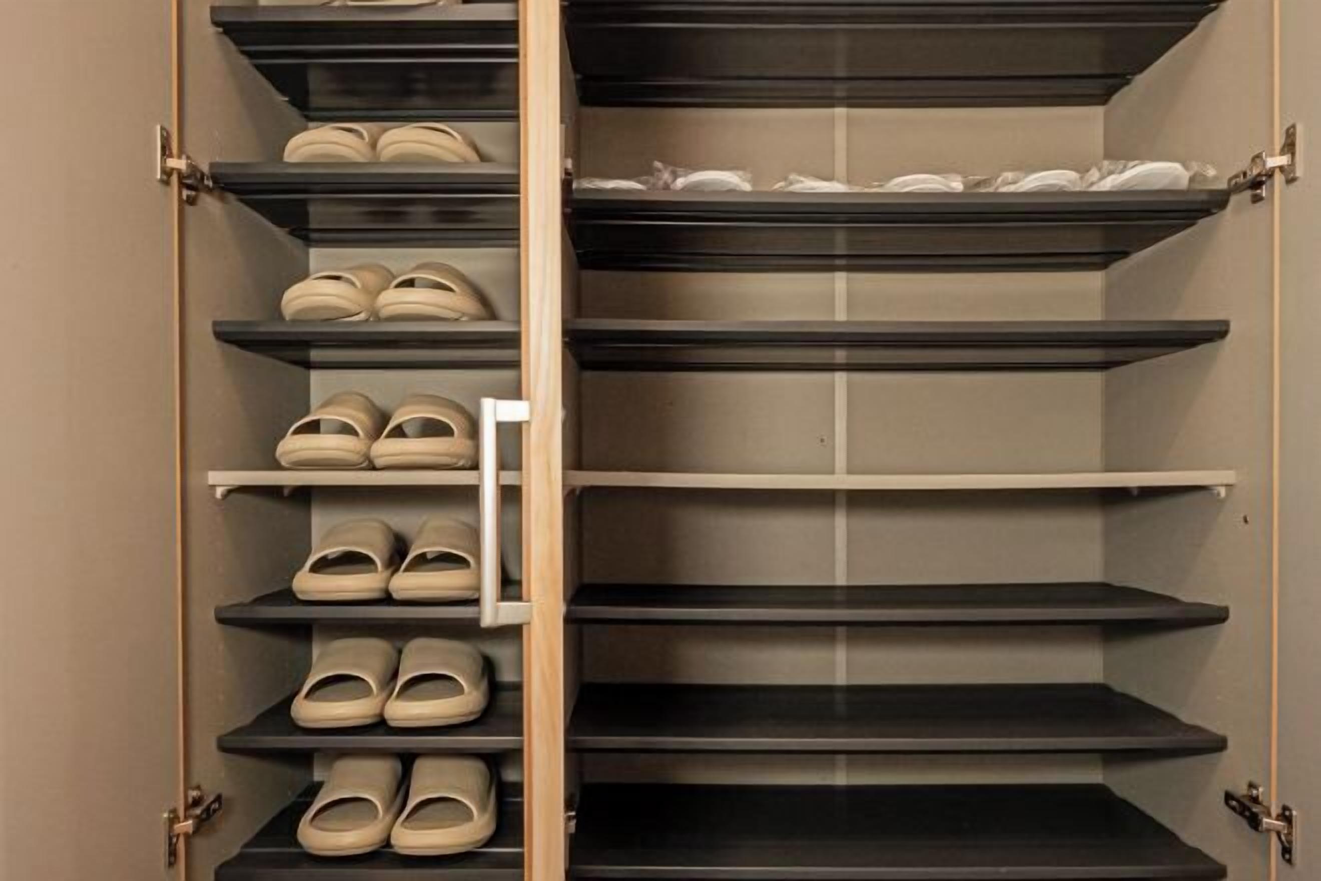 A closet with multiple shelves, some with shoes and others empty.