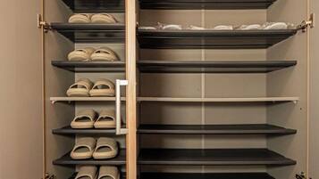 A closet with multiple shelves, some with shoes and others empty.