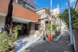 A narrow urban street with a modern two-story building featuring a balcony and a small garden area. - 1-min sta/Asakusa/Ueno/Ginza/Skytree/Narita/Haneda (Tokyo)