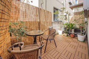 A small outdoor patio with a table and chairs, surrounded by potted plants and a bamboo fence. - 1-min sta/Asakusa/Ueno/Ginza/Skytree/Narita/Haneda (Tokyo)