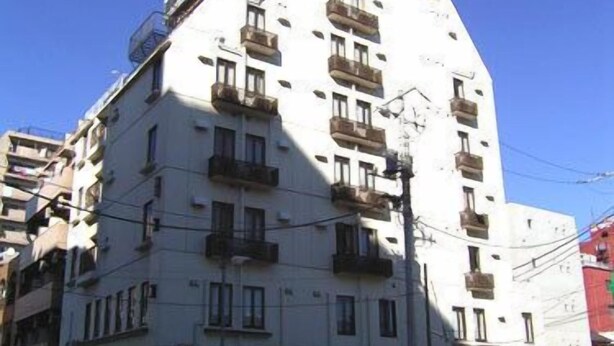 A multi-story building with balconies, a visible sign, and parked cars. - Soho Asakusa Hotel (Tokyo)