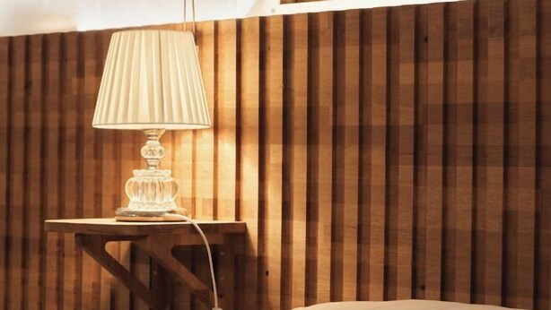 A wooden slatted wall, a bedside table with a lamp, and a bed. - Sohwa Mansion [8min STN] / Luggage Keep available (Seoul)