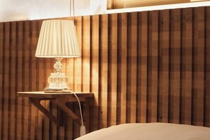 Una pared de listones de madera, una mesita de noche con una lámpara y una cama.