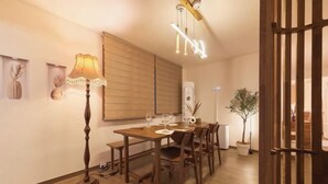 A dining area with a wooden table, chairs, a floor lamp, and a ceiling light fixture. - Sohwa Mansion [8min STN] / Luggage Keep available (Seoul)