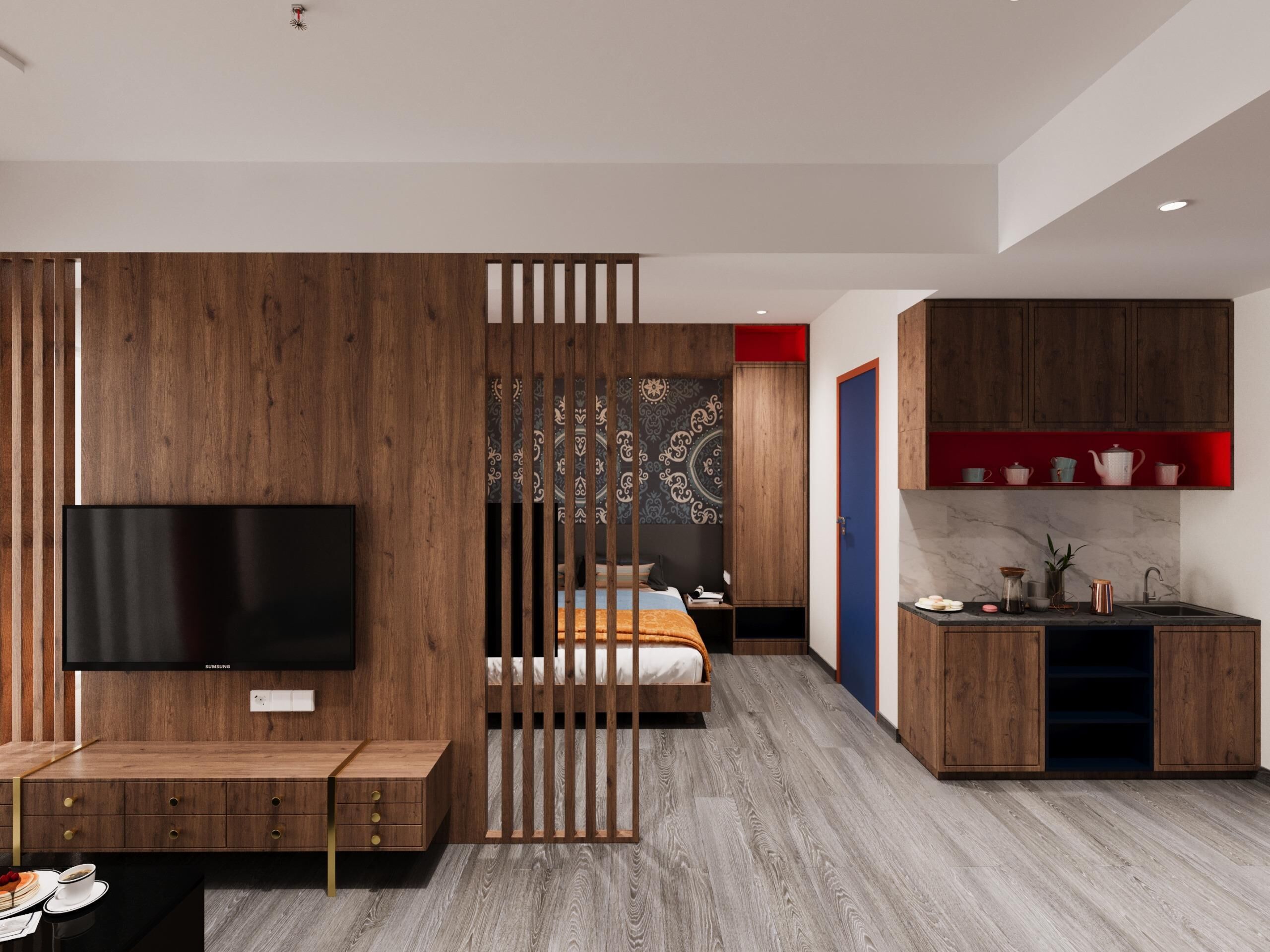 A modern hotel room with a wooden partition, a flat-screen TV, a bed, a desk, and a kitchen area with cabinets and a sink.