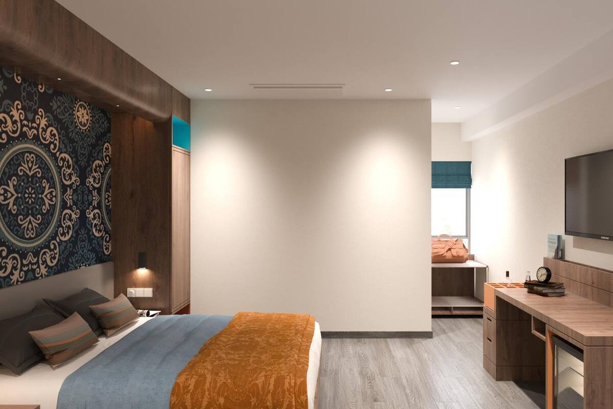 A modern hotel room with a large bed, a desk, and a television.
