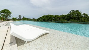 A poolside area with a white lounge chair and a tiled deck. - Beachside 2BR 200 m to BangTao beach (Choeng Thale)