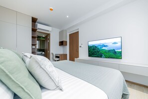 Una camera da letto moderna con un letto, una TV a parete e mobili contenitori integrati.