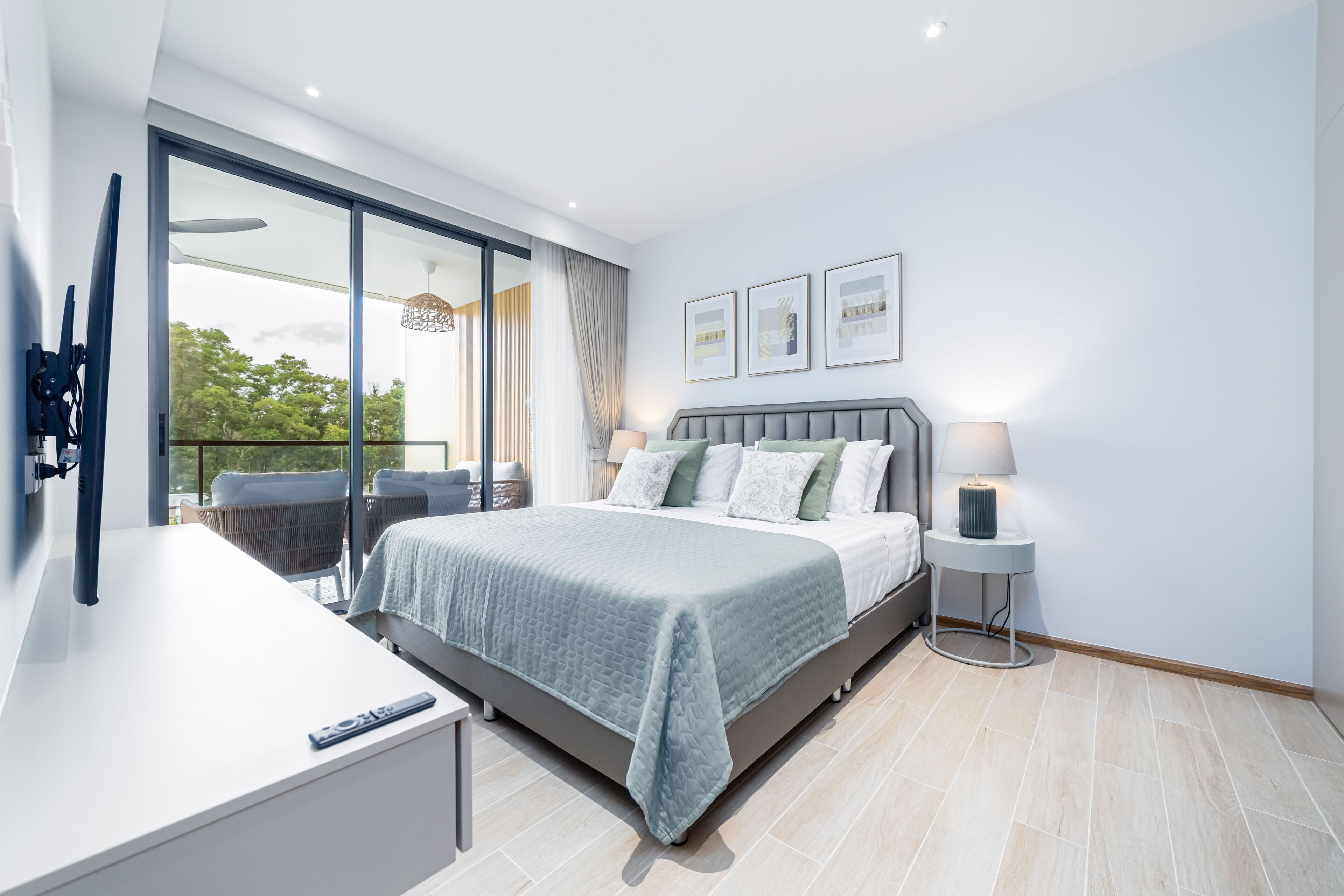 Un dormitorio moderno con una cama grande, una mesita de noche, una lámpara y vistas al exterior.