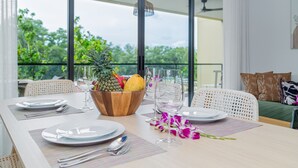 A dining table set with plates, cutlery, and a fruit bowl. - Beachside 2BR 200 m to BangTao beach (Choeng Thale)
