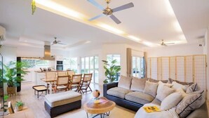 A modern living room with a sofa, coffee table, and dining area. - Kira Japandi Escape with Sauna & Rooftop cinema (Hua Hin)