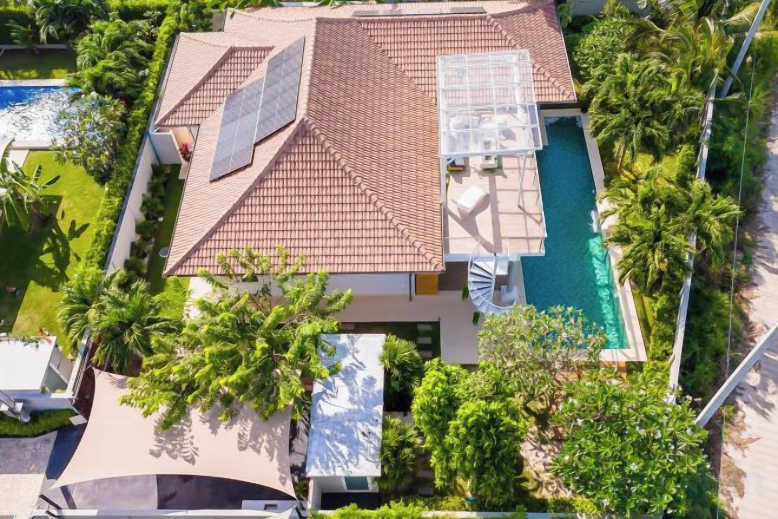 A residential building with a swimming pool, solar panels, and lush greenery.
