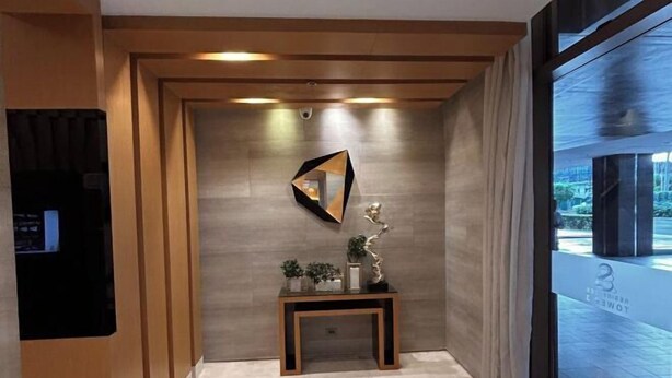 A modern hallway with a wooden ceiling, a wall-mounted mirror, a small table with decorative items, and a large window with a view of the outside. - S Residences, 32sqm Spacious Tower-3 Mall of Asia (Pasay)