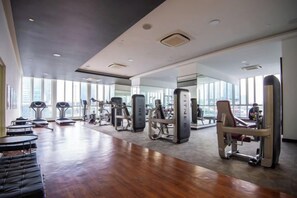 Une salle de sport équipée de machines de cardio, de matériel de musculation et dotée d’un plancher en bois.
