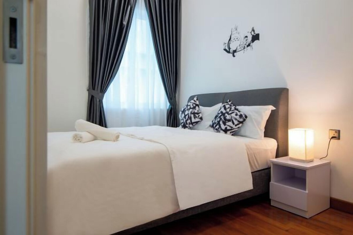 Habitació d'hotel amb un llit, una tauleta de nit amb una làmpada i una obra d'art penjada a la paret.