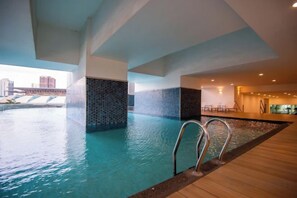 Una piscina interior con vista a un puente, rodeada de un diseño arquitectónico moderno.