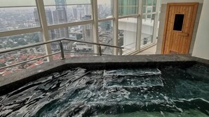 Un bain à remous avec vue sur la ville, une porte en bois et une rambarde en métal.