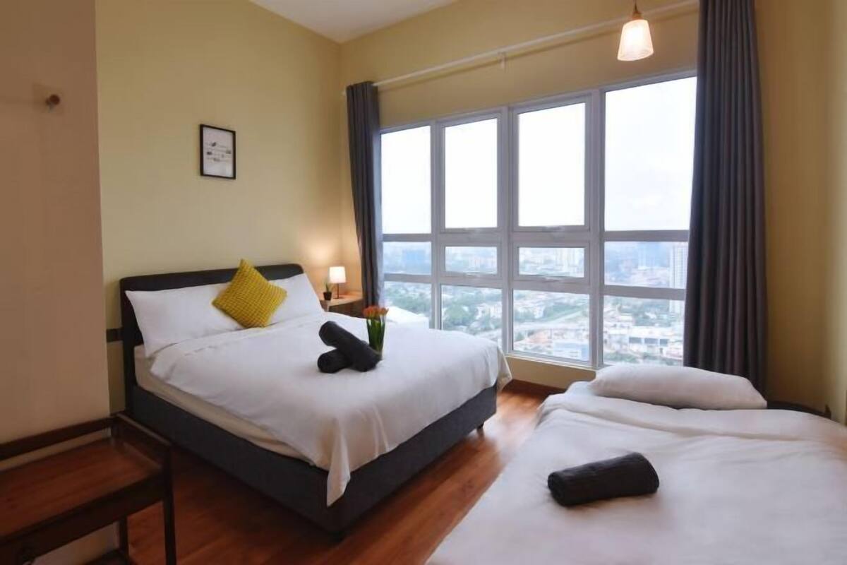 Une chambre d’hôtel avec une grande fenêtre, un lit, une table de chevet et une petite table.